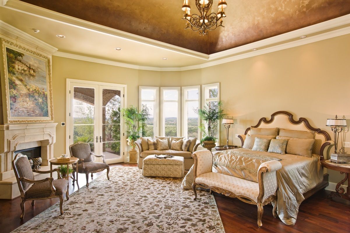 Luxurious bedroom with ornate furniture, a fireplace, and a gold-colored ceiling.