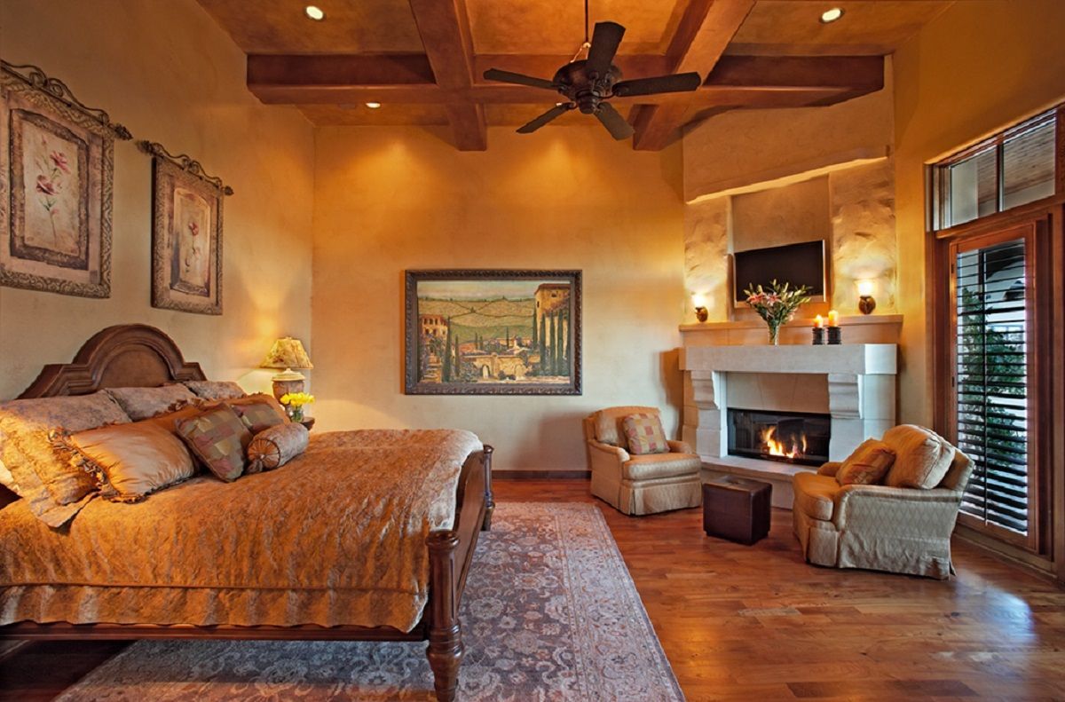 Luxurious bedroom with large bed, fireplace, seating area, and outdoor view through a wooden door.
