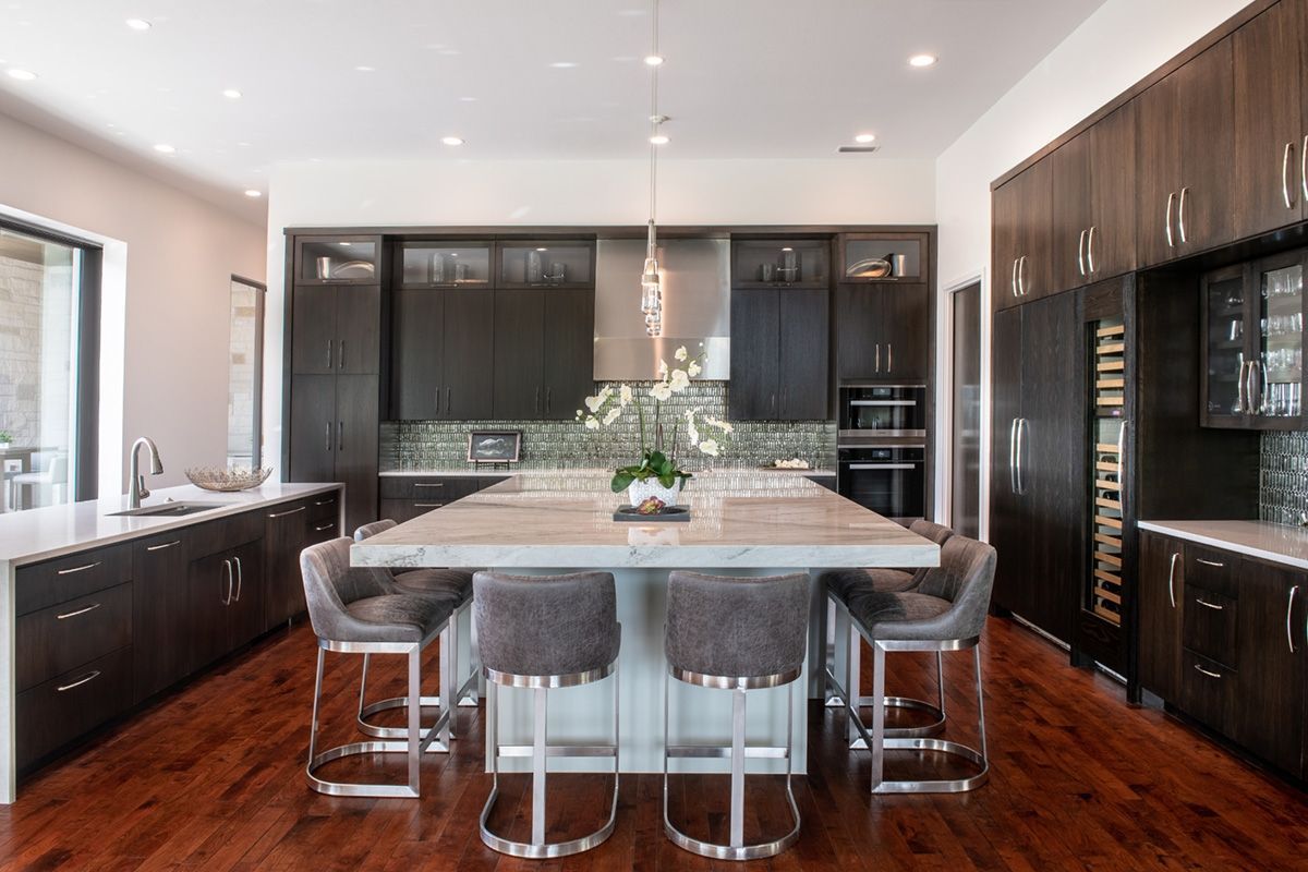Modern kitchen with dark wood cabinets, large island with seating, and hardwood floors.