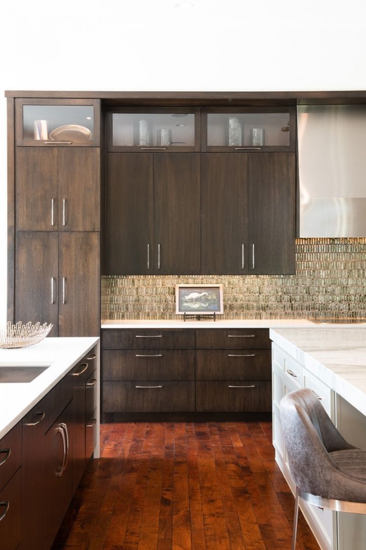 Modern kitchen with dark brown cabinets, wood floors, and a stainless steel hood.