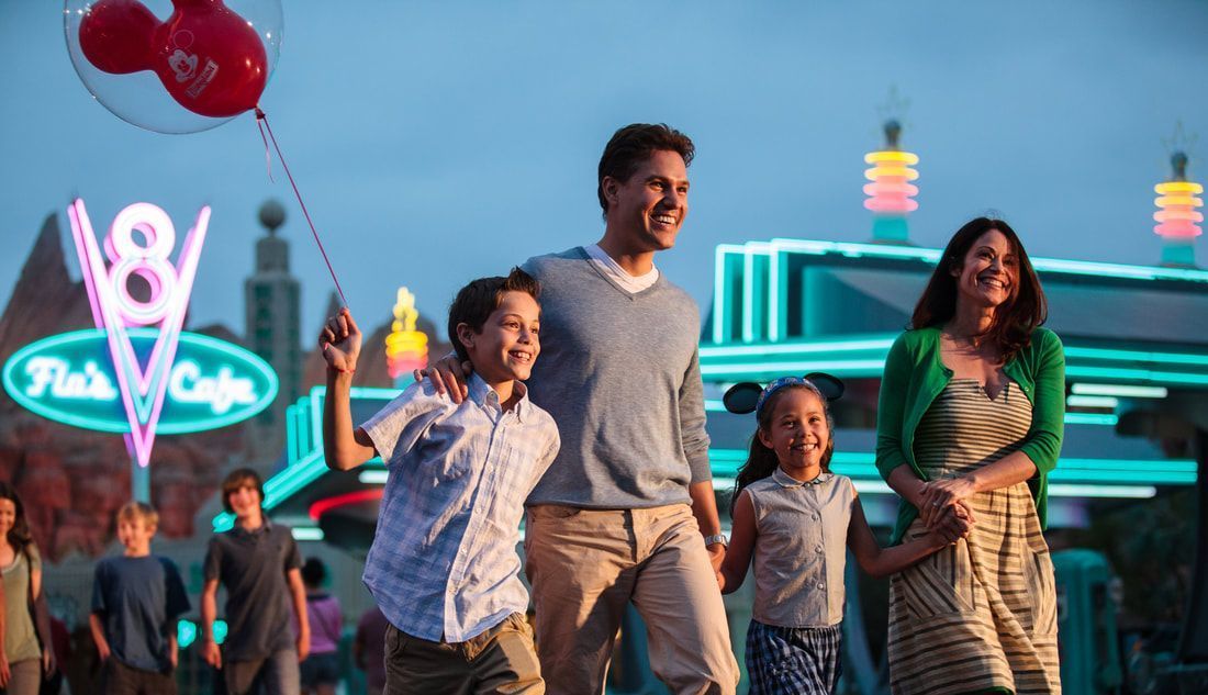 Smiling family walking down a street at Disney World holding a balloon and wearing mousin