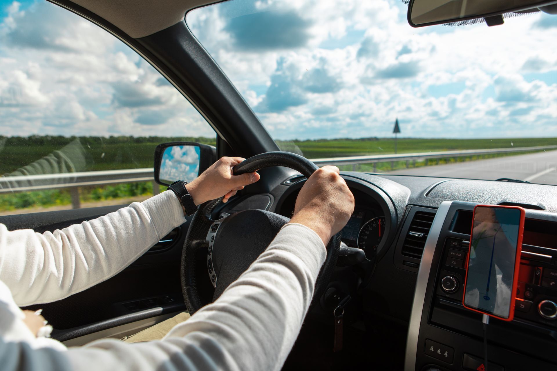 Hand holds a black steering wheel.