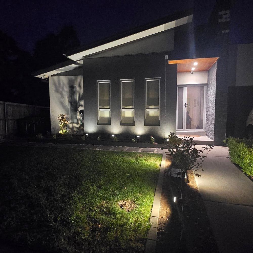The Front of a House is Lit Up at Night — Professional Electrical & Data Pty Ltd in Bonner, ACT
