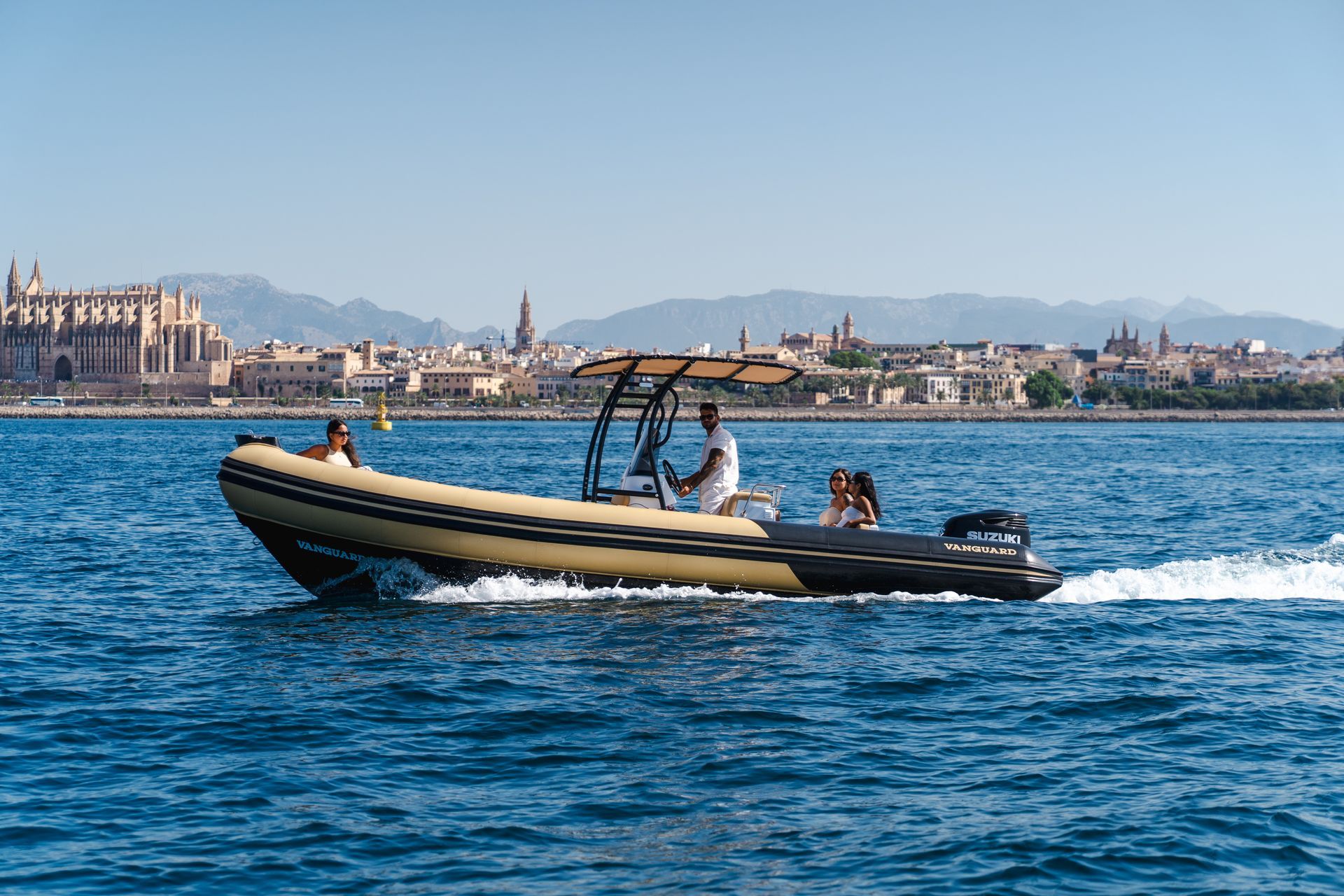 Barco en el agua con gente, con la costa al fondo. Día soleado.