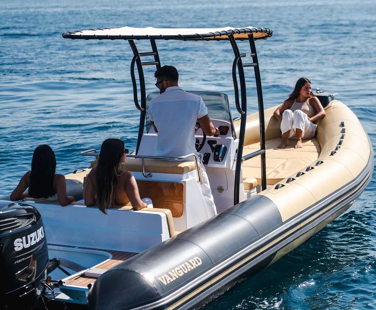 Personas disfrutando de una lancha neumática Vanguard en el agua. Embarcación beige y negra con motor Suzuki.
