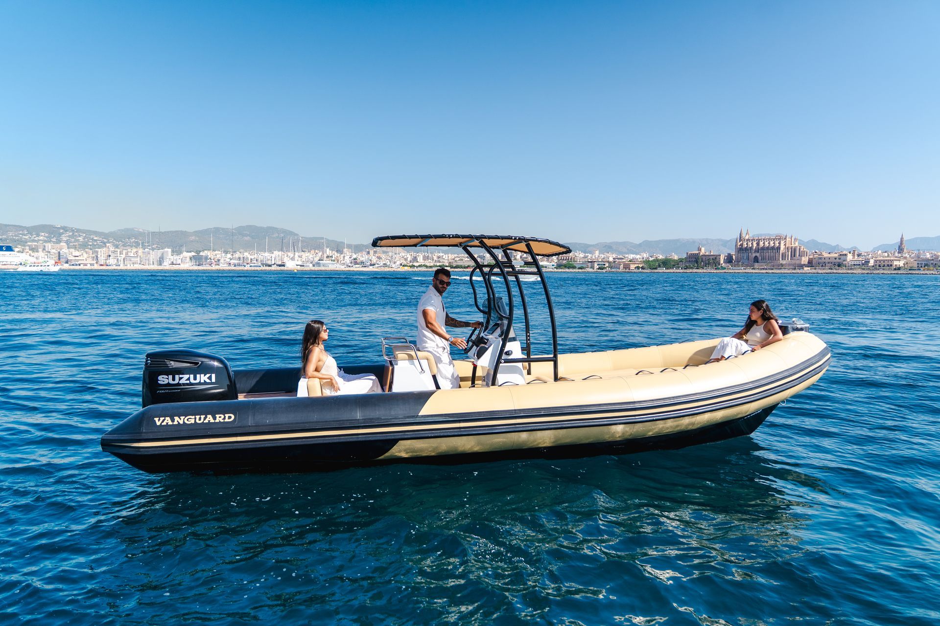 Barco con tres personas en el agua, día soleado. Vista del horizonte de la ciudad al fondo.