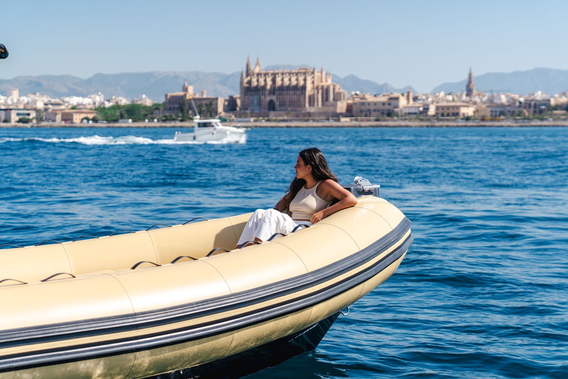 Mujer en un barco, contemplando el horizonte de una ciudad con una gran catedral en un día soleado.