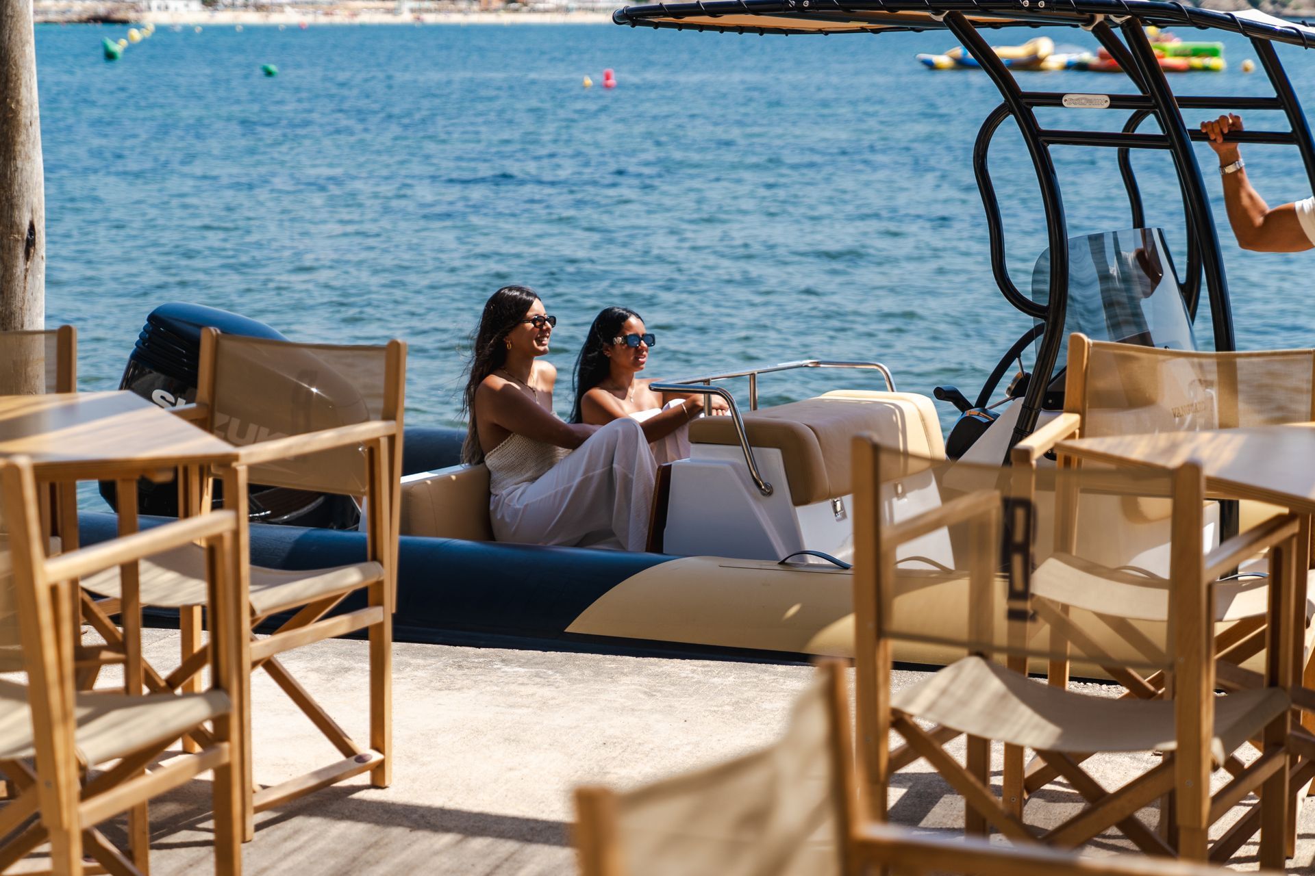 Dos mujeres con vestidos blancos en un barco cerca de una playa.