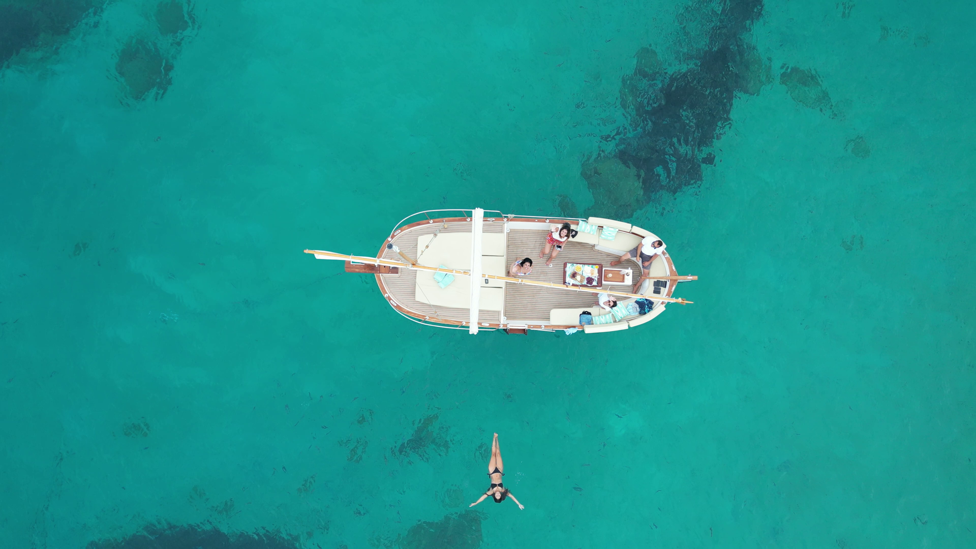 Mujer nadando en aguas turquesas cerca de un barco.