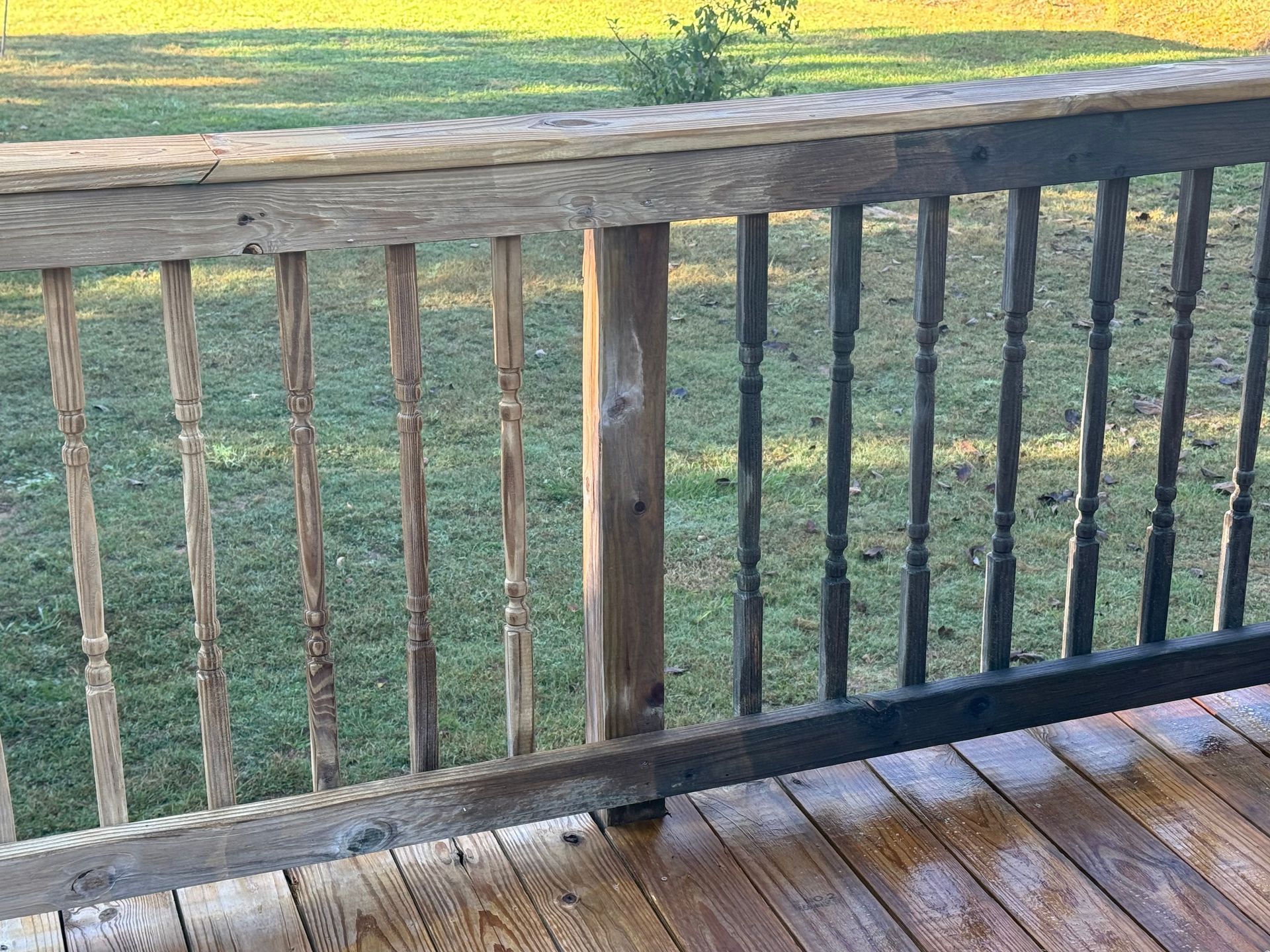 Wooden deck railing partially cleaned, showing the difference between weathered and freshly cleaned wood.