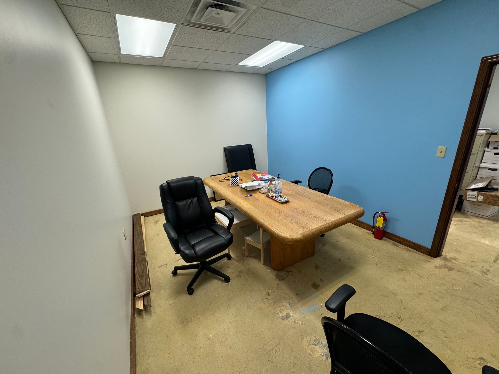 An office with a large wooden table and chairs, blue and white walls, and a fire extinguisher.
