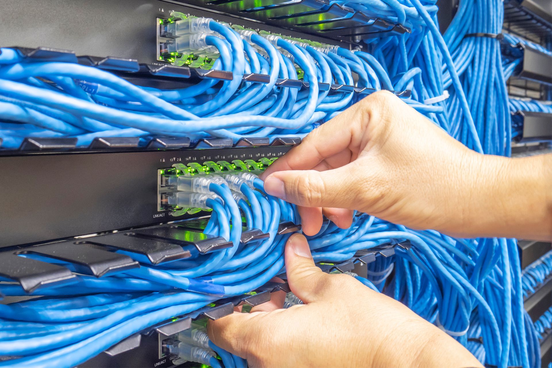 A person is working on a server with blue wires
