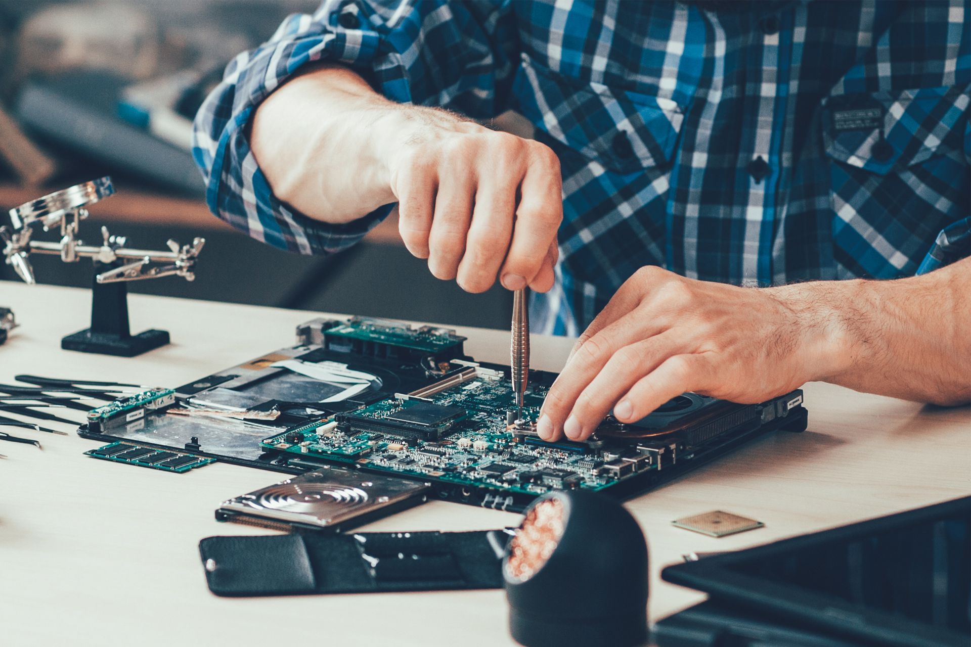 A man is working on a motherboard with a screwdriver