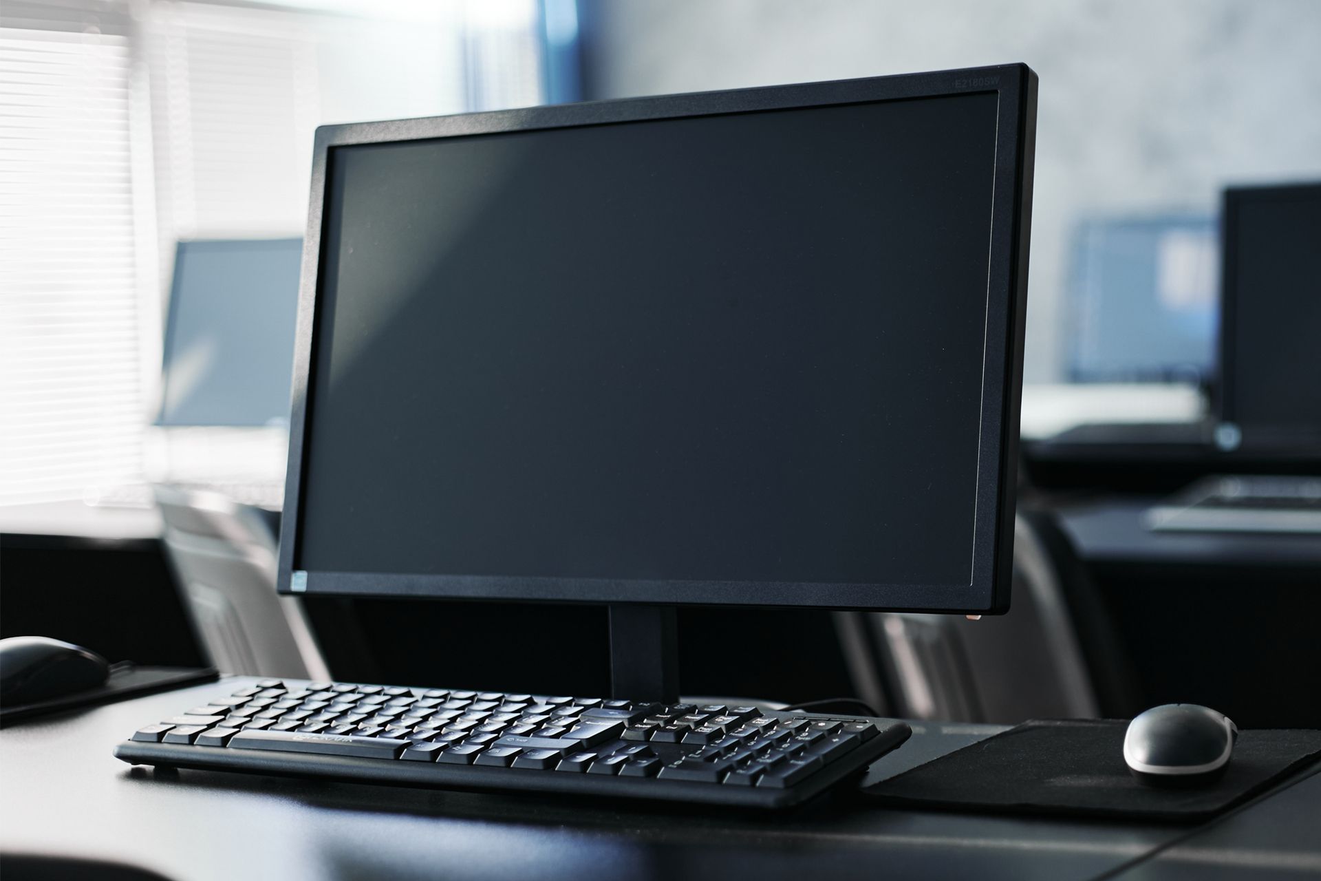 A computer monitor is sitting on a desk next to a keyboard and mouse