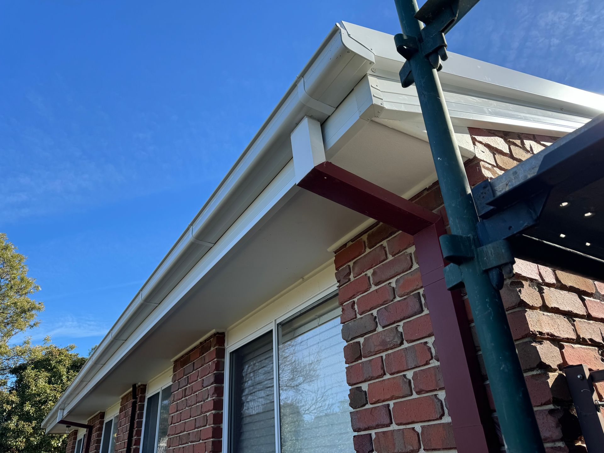 A Brick Building With a White Gutter and a Red Roof — CBR Maintenance In Curtin, ATC