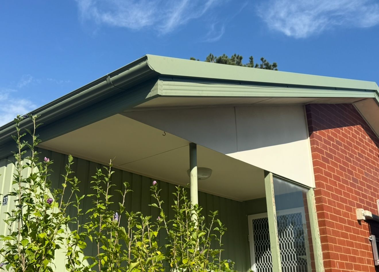 A brick house with a green roof and a porch — CBR Maintenance In Tuggeranong, ATC