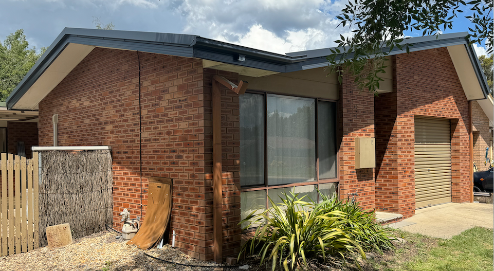 A Brick House With a Garage and a Fence in Front of It — CBR Maintenance In Curtin, ATC