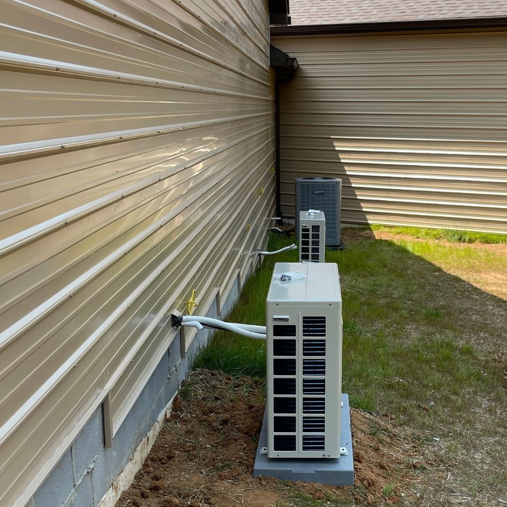 Two air conditioners are installed on the side of a house.
