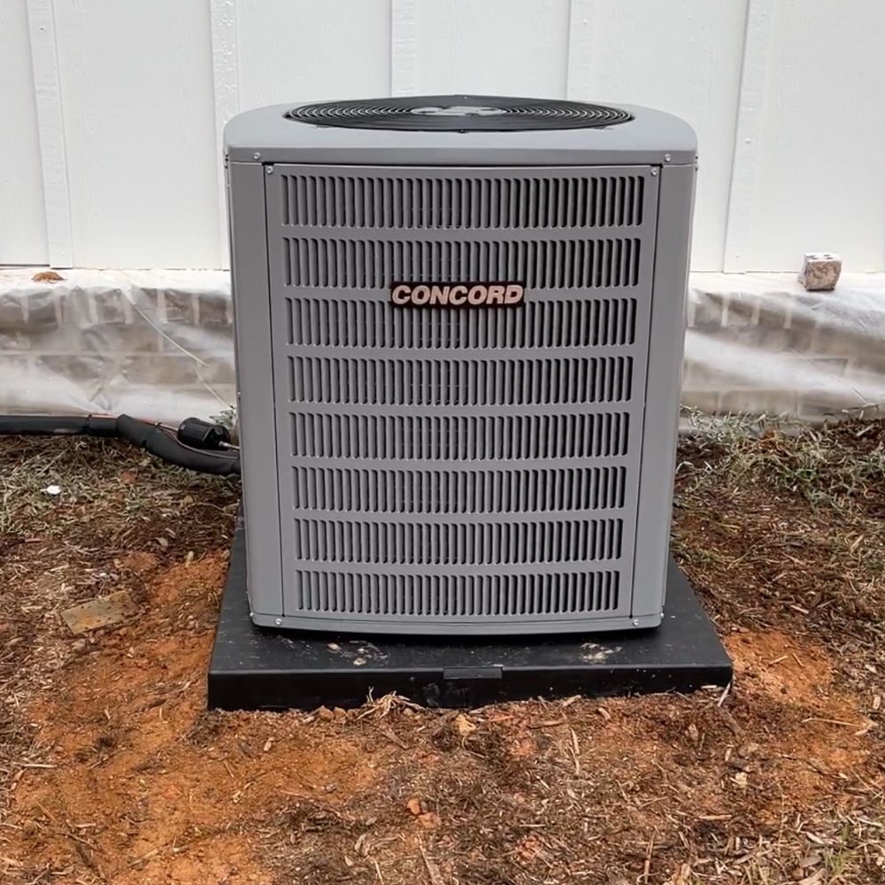 A concord air conditioner is sitting in the dirt