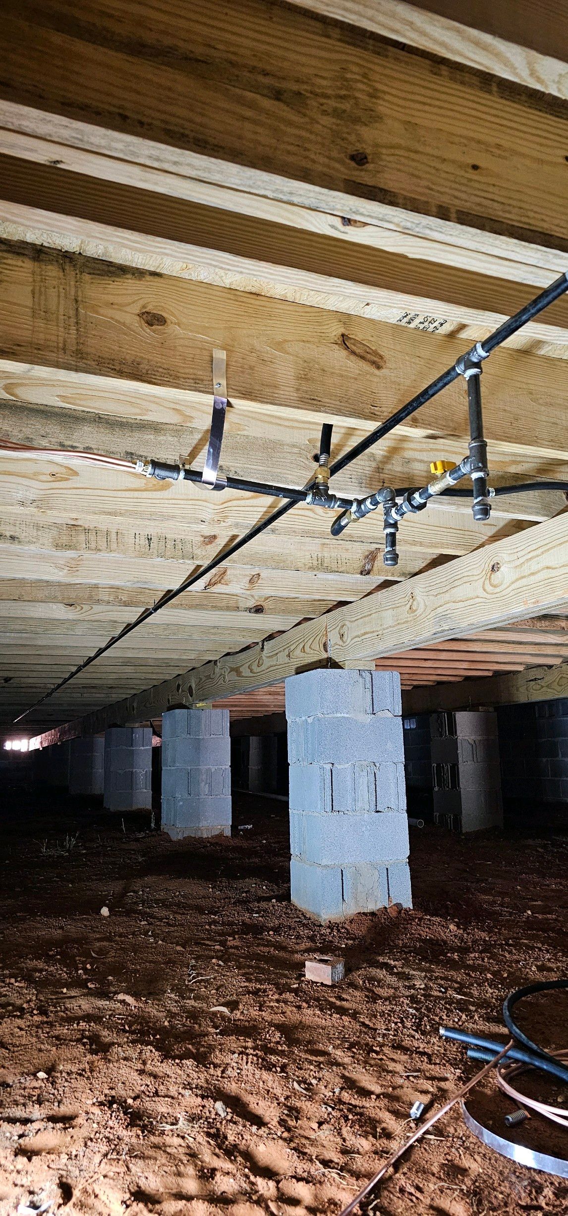 A crawl space under a house with a lot of wires hanging from the ceiling.