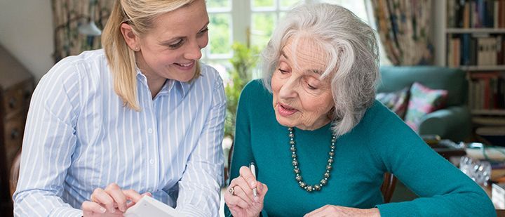 A woman is helping an elderly woman with a piece of paper.