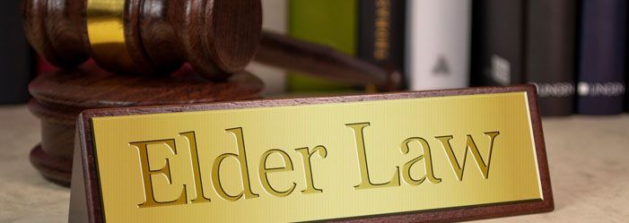 A wooden gavel and a sign that says `` elder law '' on a table.