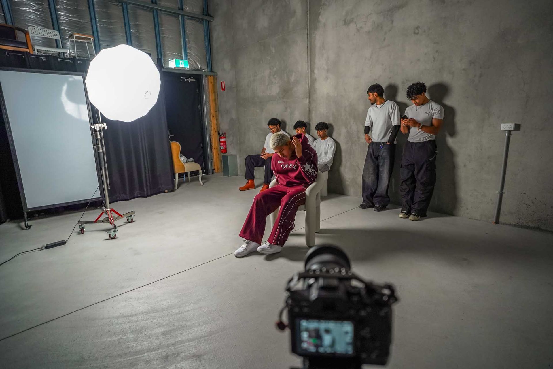 Man singing into a microphone on stage, under blue lights.