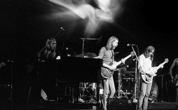 A black and white photo of a band performing live on stage with instruments.