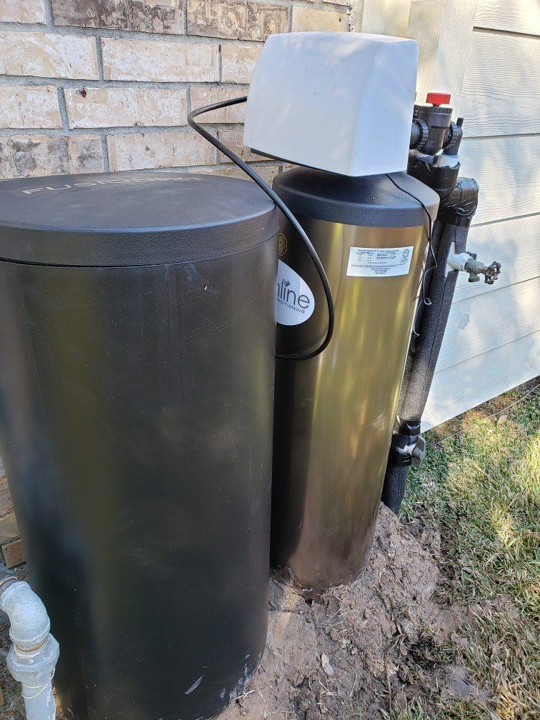 Water softener system next to a brick wall and a dirt mound.