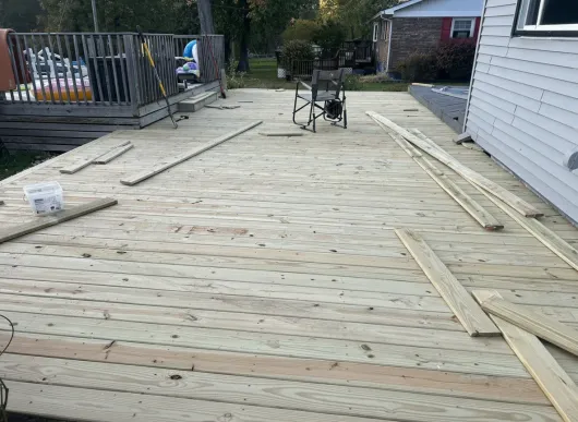 Construction of a wooden deck. Several planks of wood are laid out on the frame.