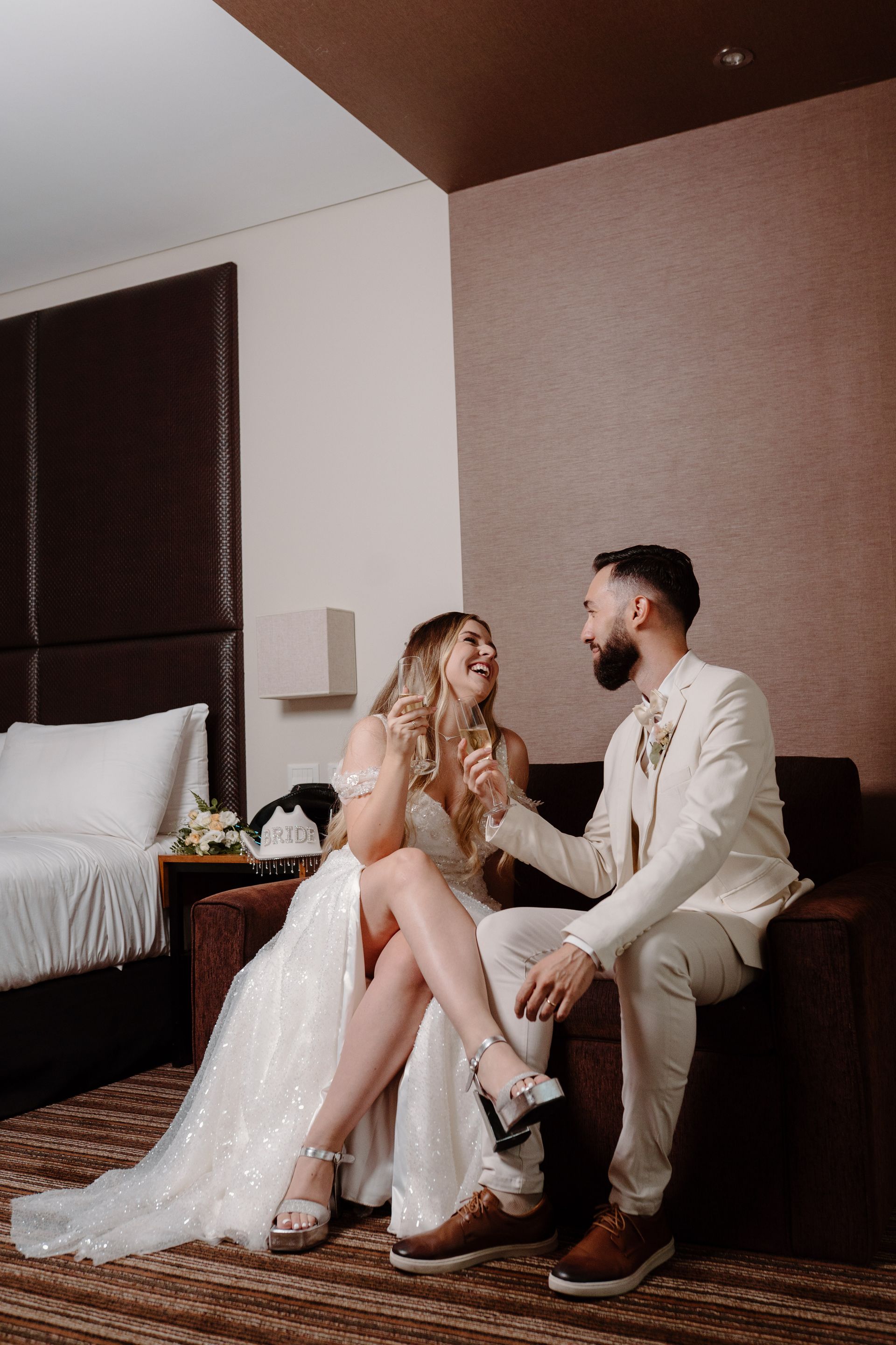 Una novia y un novio besándose frente a su fiesta de bodas.