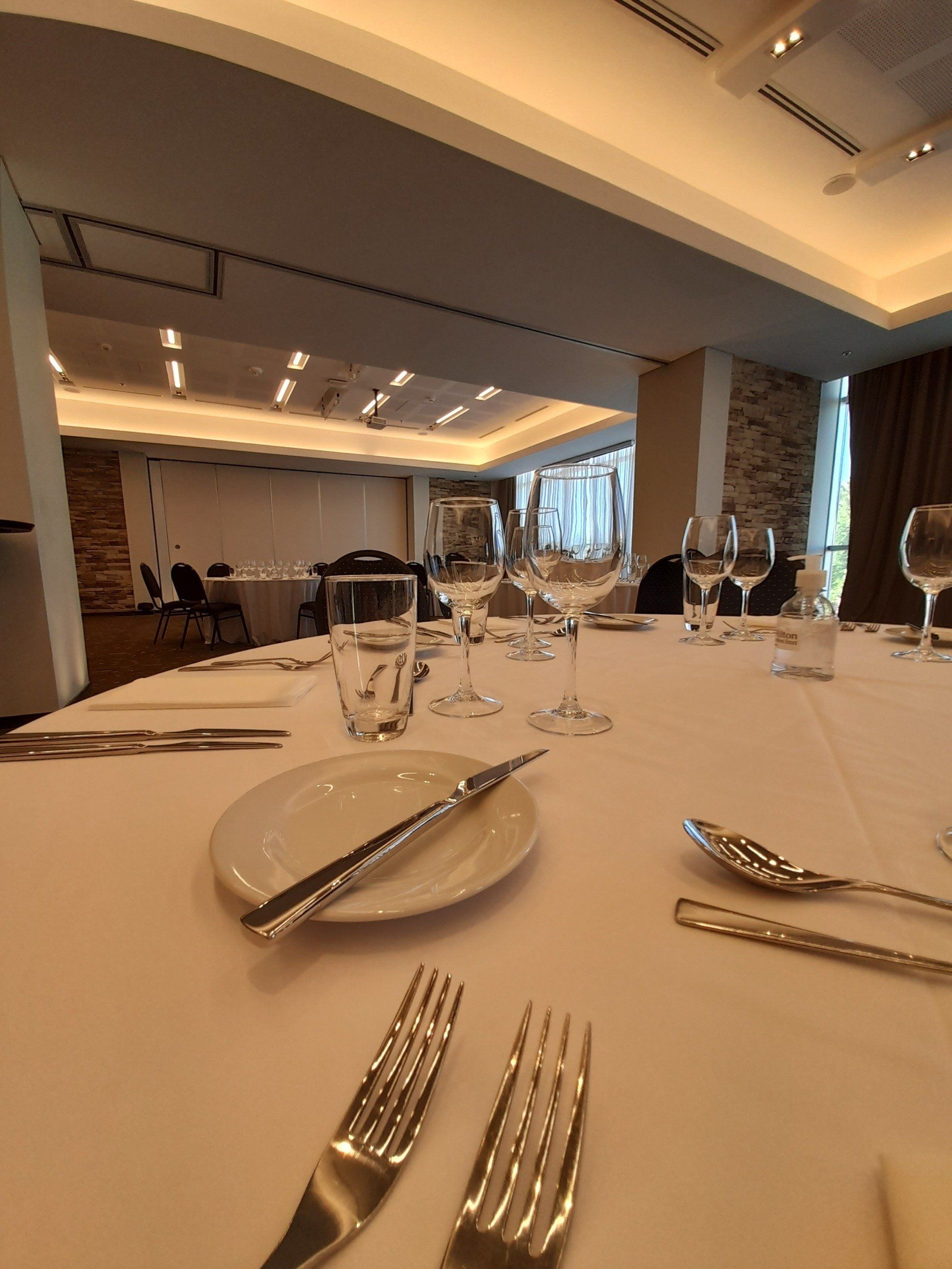 Un mantel blanco con cubiertos y copas de vino.