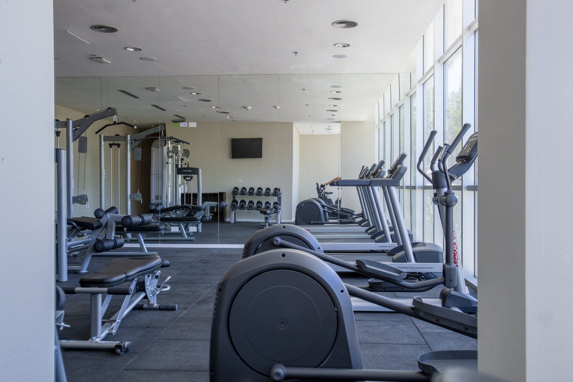 Un gimnasio grande con mucho equipamiento y muchas ventanas.
