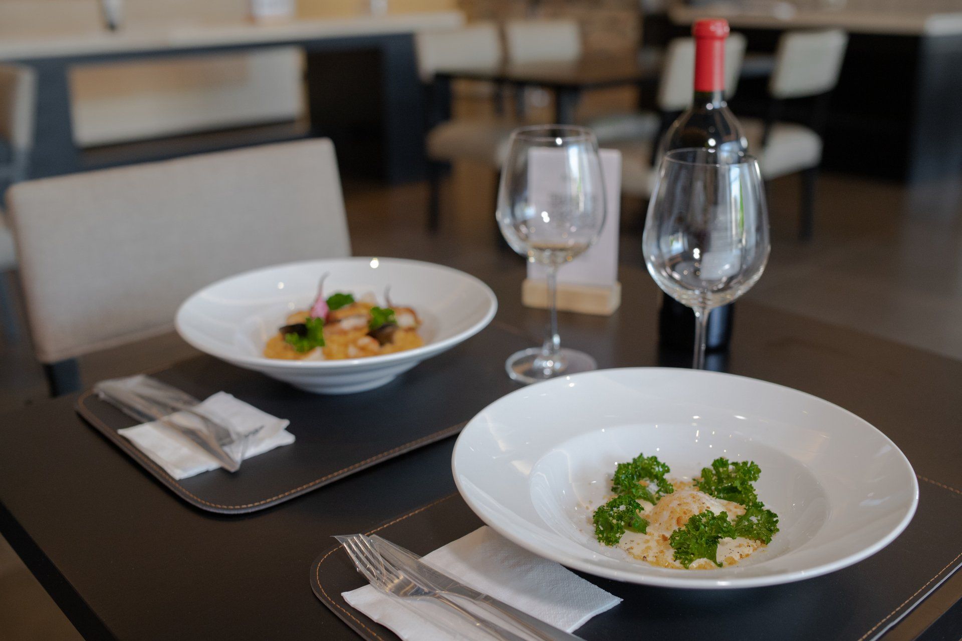 Dos tazones de comida y una copa de vino sobre una mesa en un restaurante.