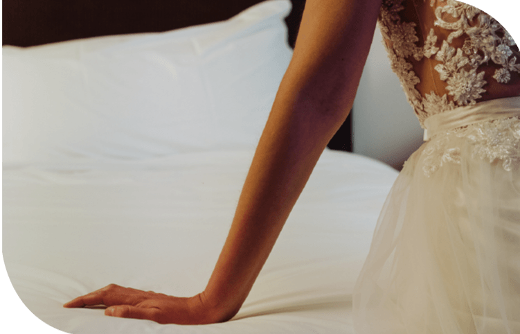 Una mujer con un vestido de novia está sentada en una cama.