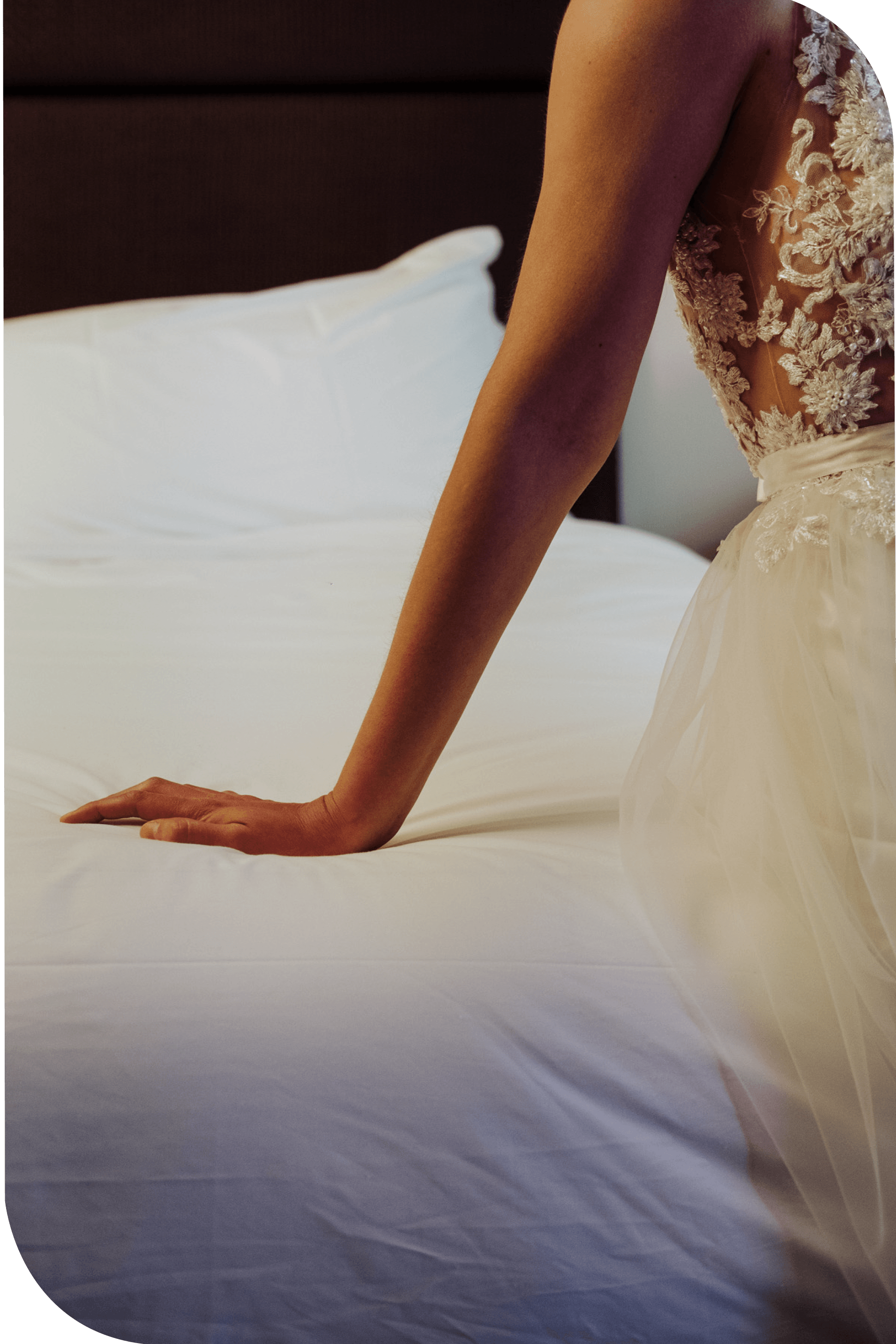 Una mujer con un vestido de novia está sentada en una cama.