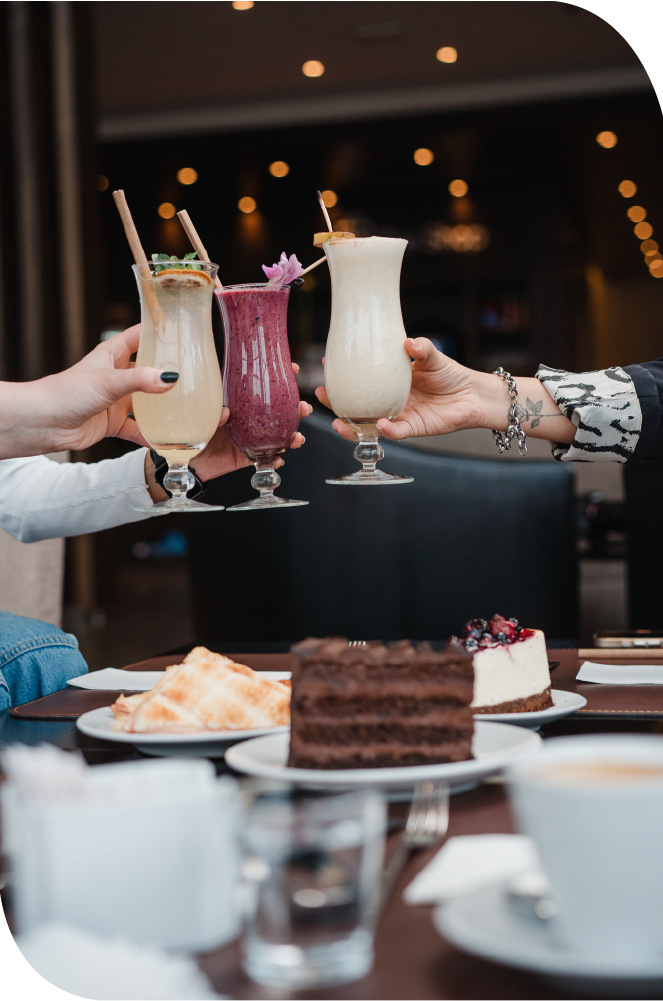 Un grupo de personas está sentada en una mesa con bebidas y un trozo de tarta.