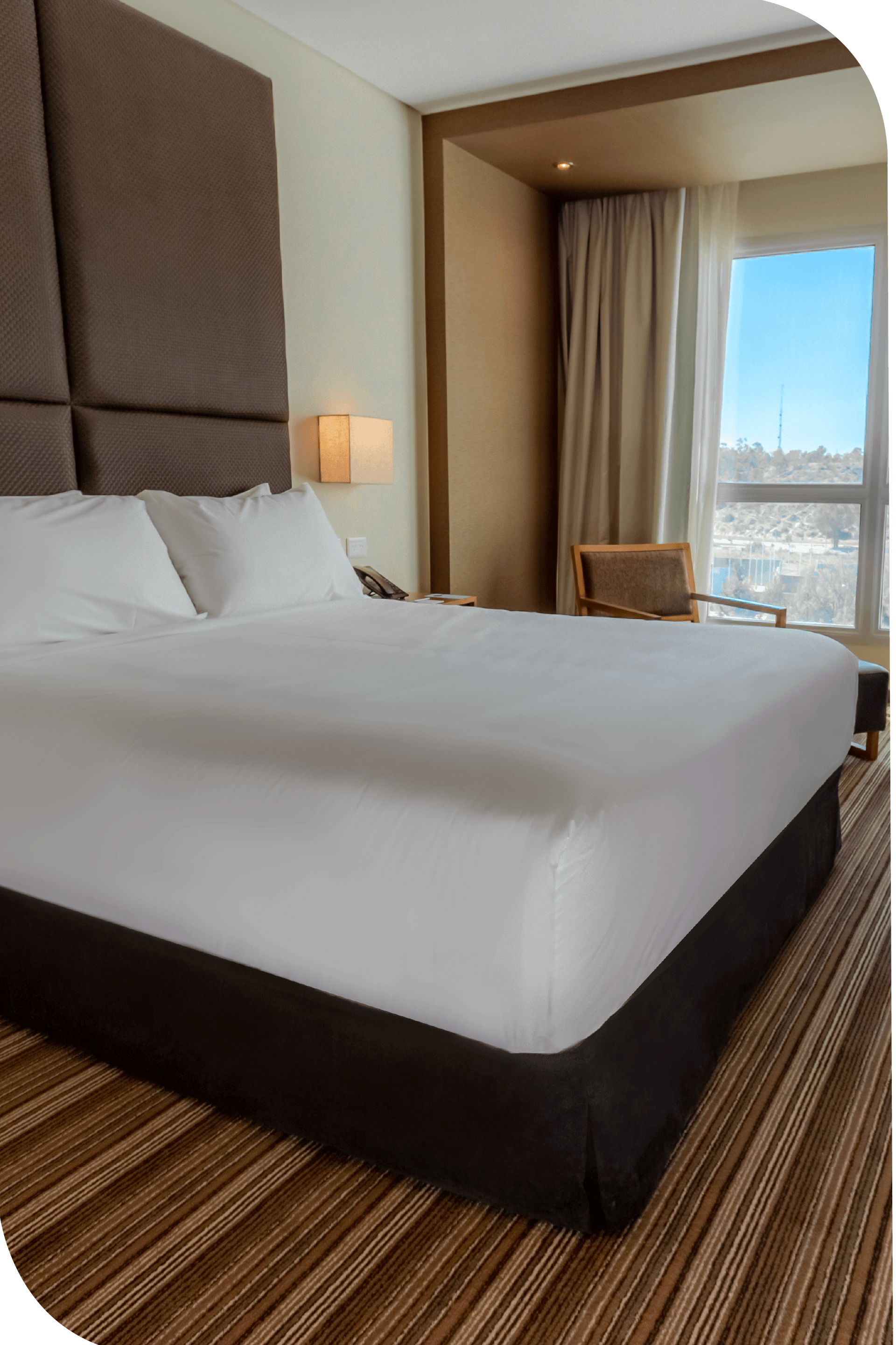 Una habitación de hotel con una cama king size y un gran ventanal.