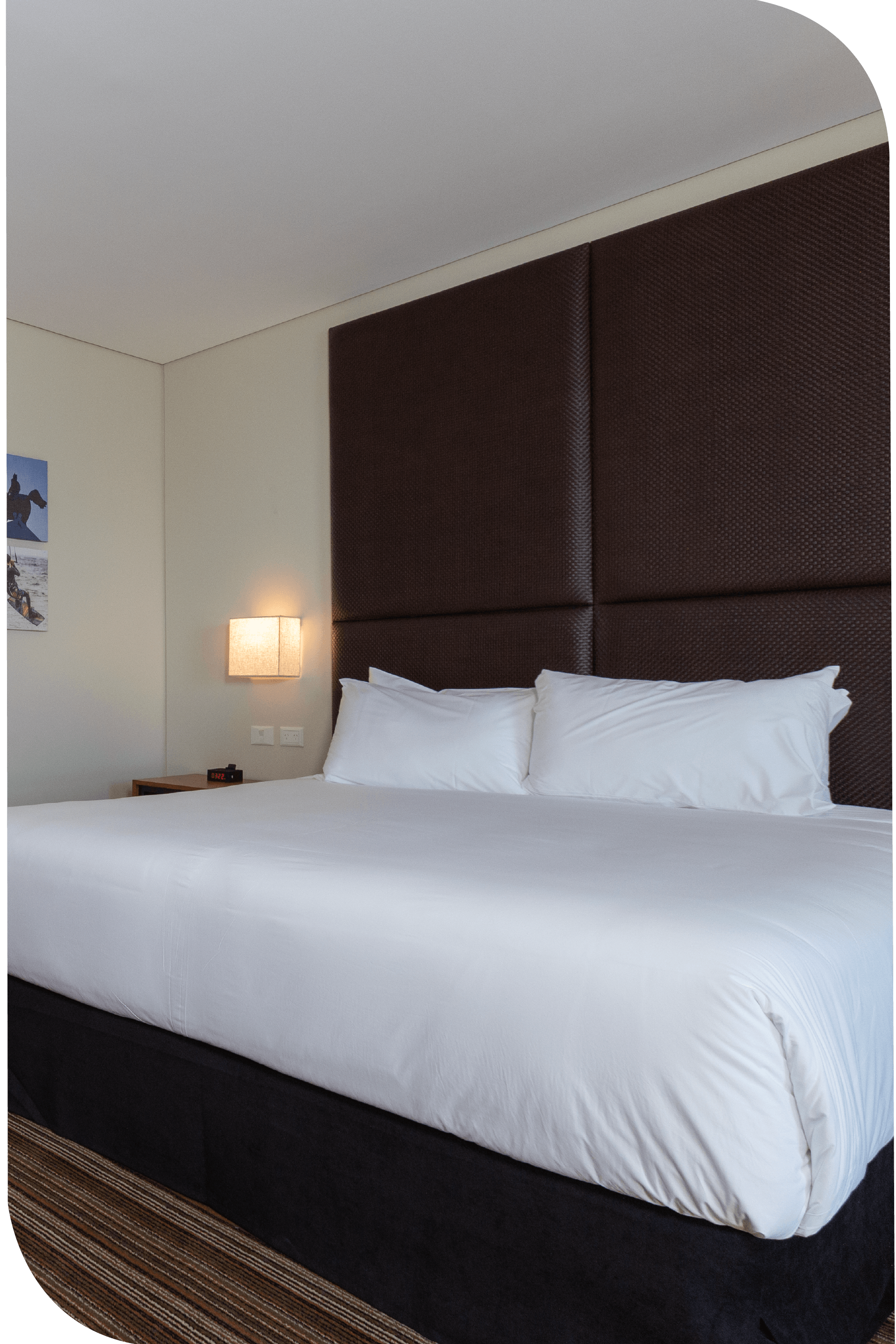 Una habitación de hotel con una cama king size y una cabecera marrón.
