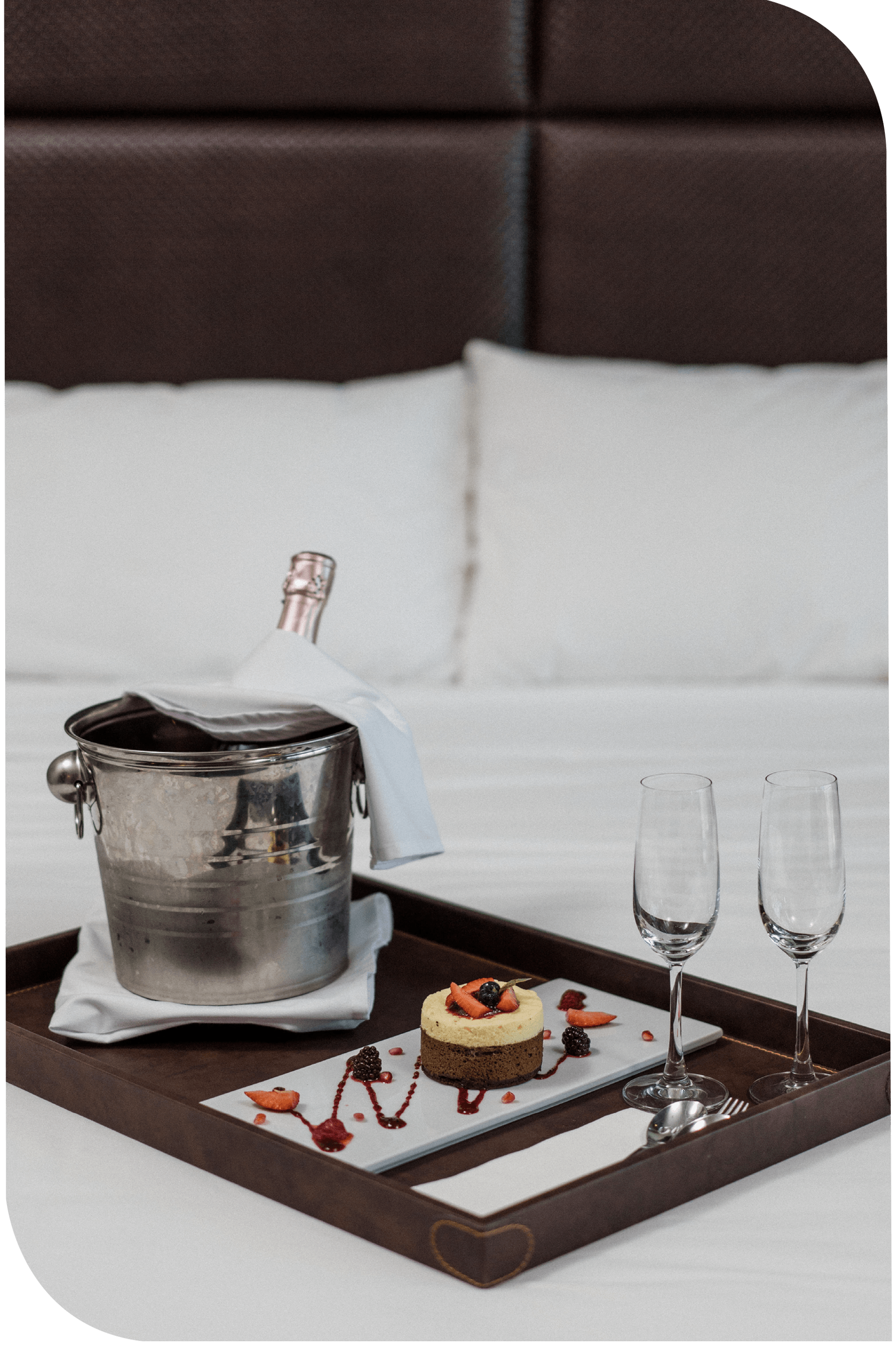 Una habitación de hotel con una bandeja de comida y champán sobre la cama.