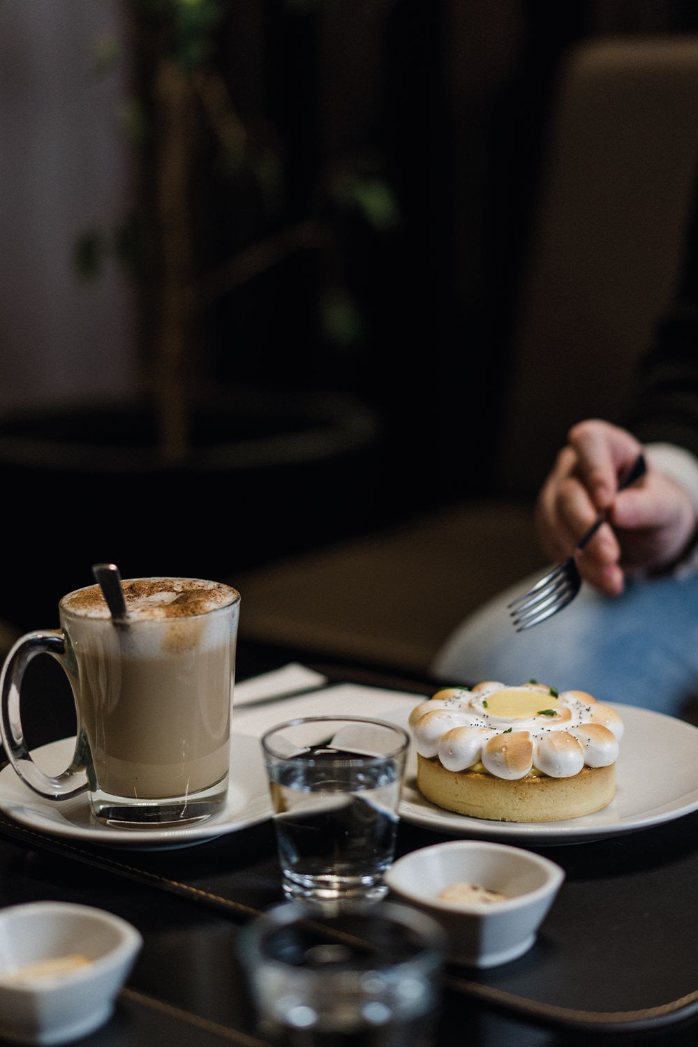 Una persona está sentada a una mesa con un plato de comida y una taza de café.