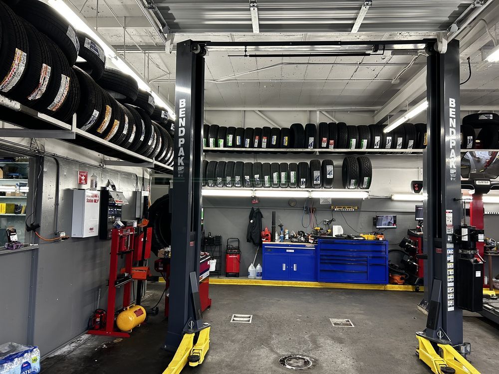 A garage with a lot of tires and a lift that says dunlop