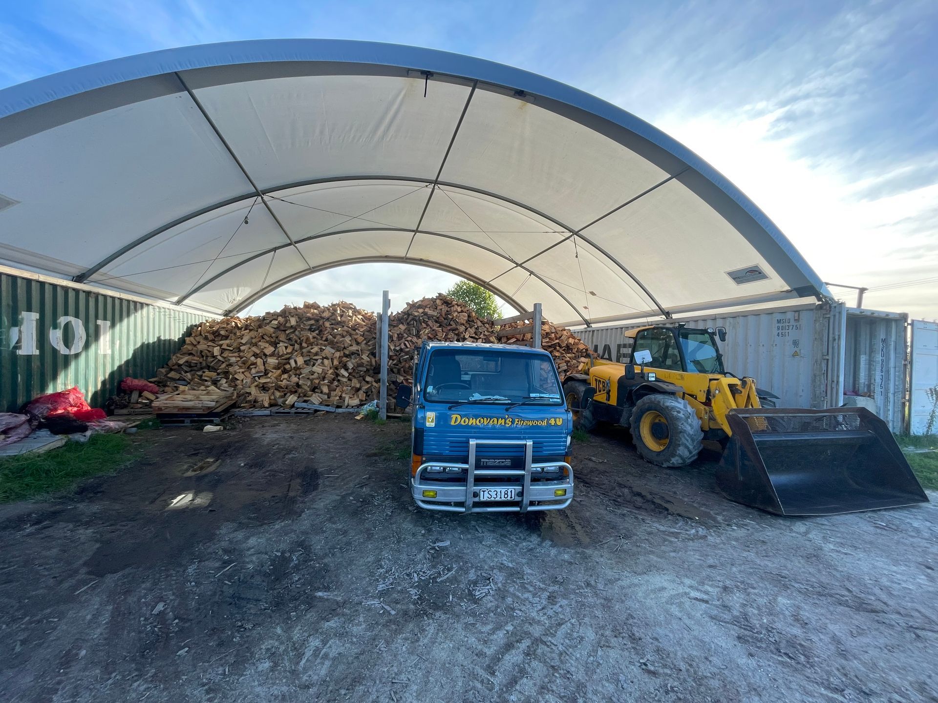 A truck and a bulldozer are parked under a canopy.