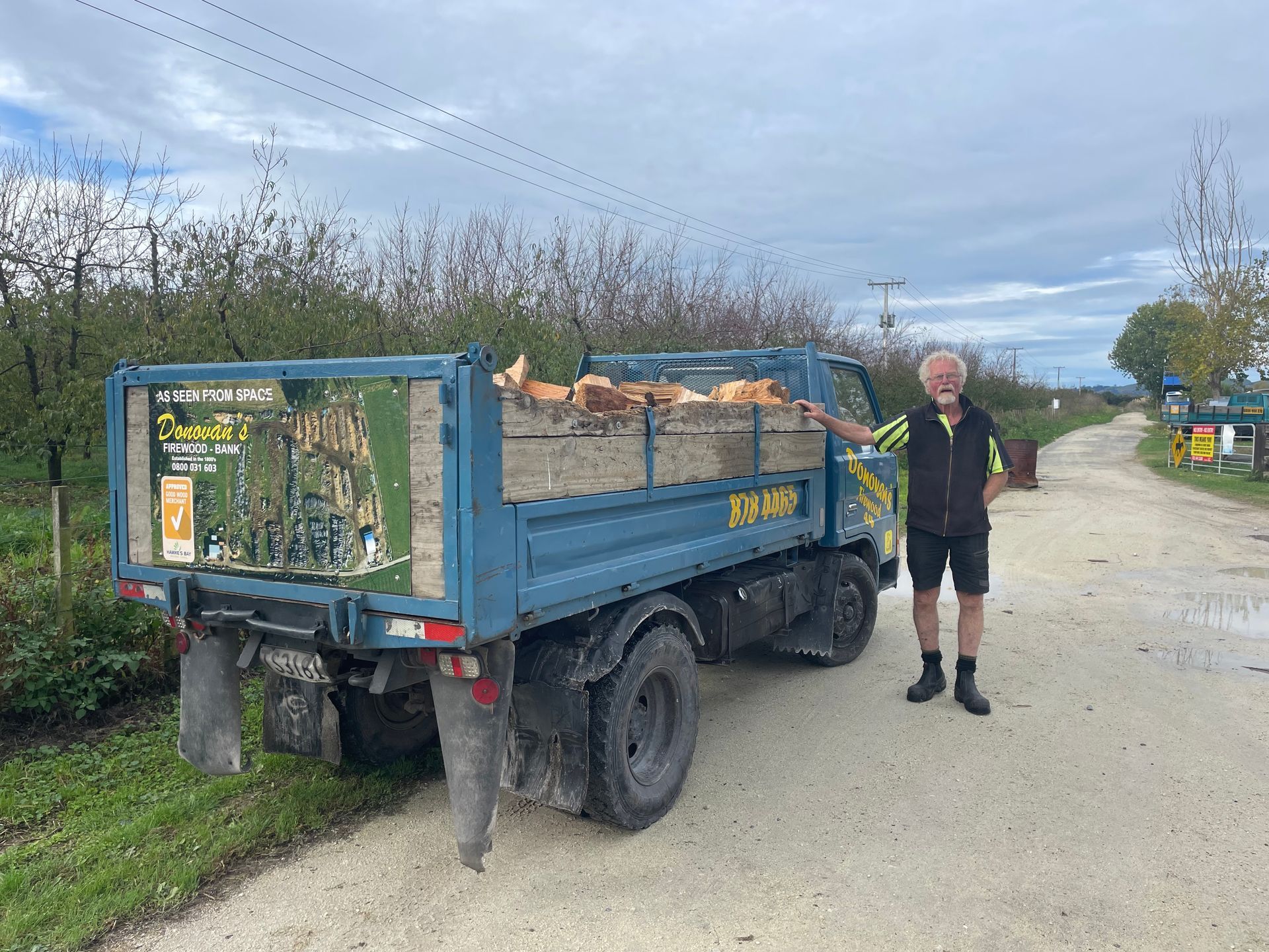 A man is standing next to a blue dump truck.