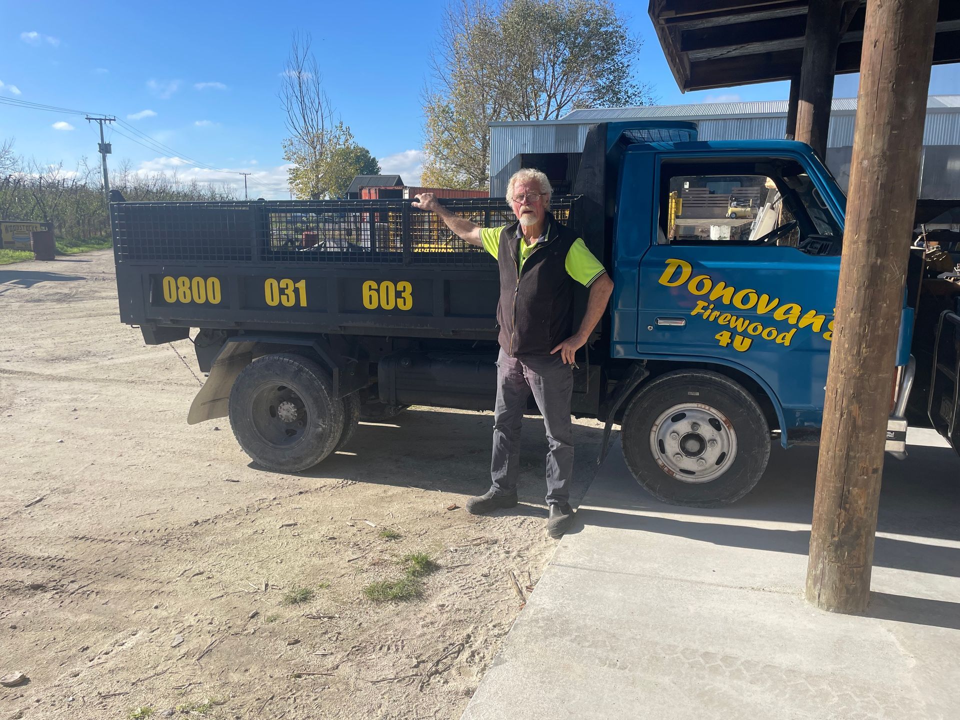 A man is standing in front of a dump truck.