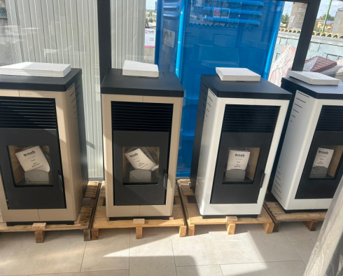 Pellet di combustibile in una paletta con un camino acceso sullo sfondo.