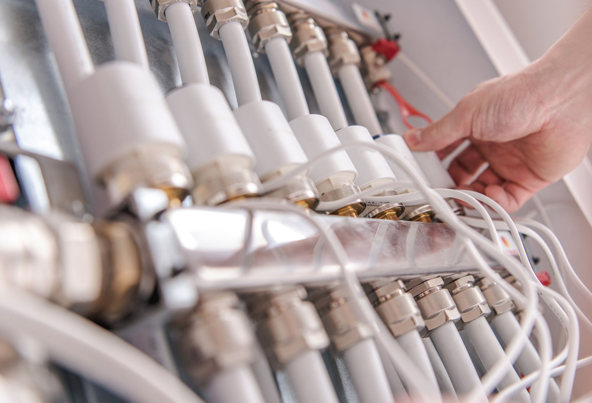 Regolazione manuale di tubi bianchi e cavi collegati a un collettore metallico.