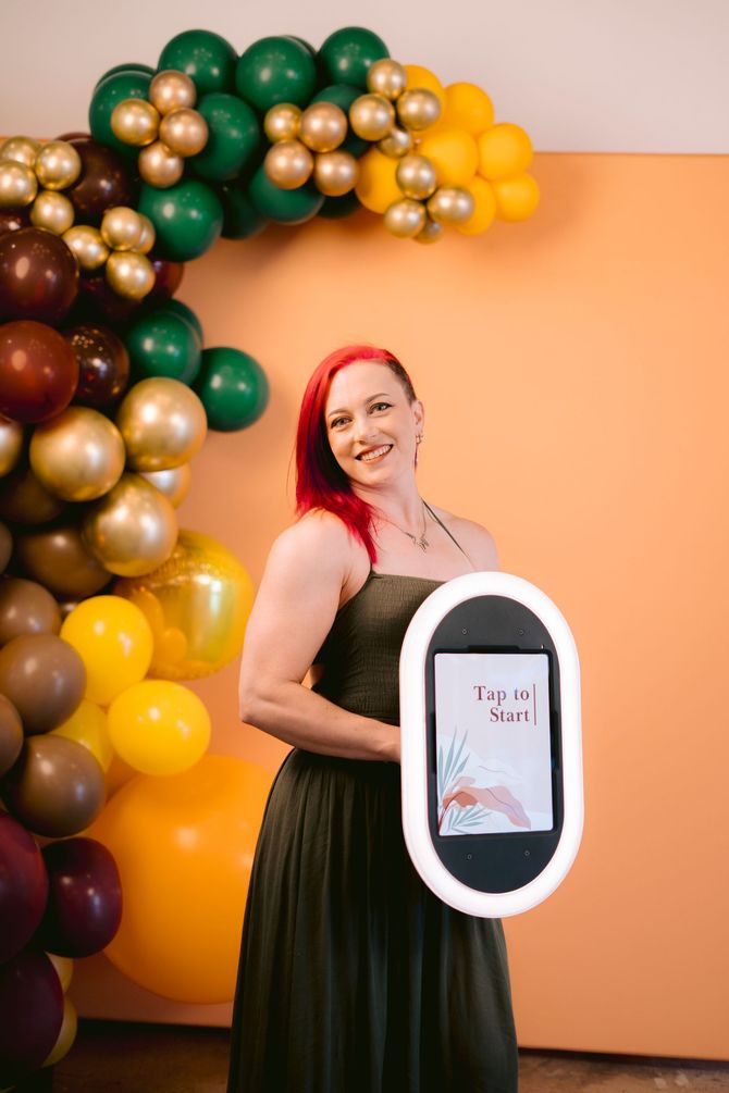 Two women laughing and posing at an iPad-powered EverGlow Booths photo booth in Boston, MA with colorful balloon backdrop