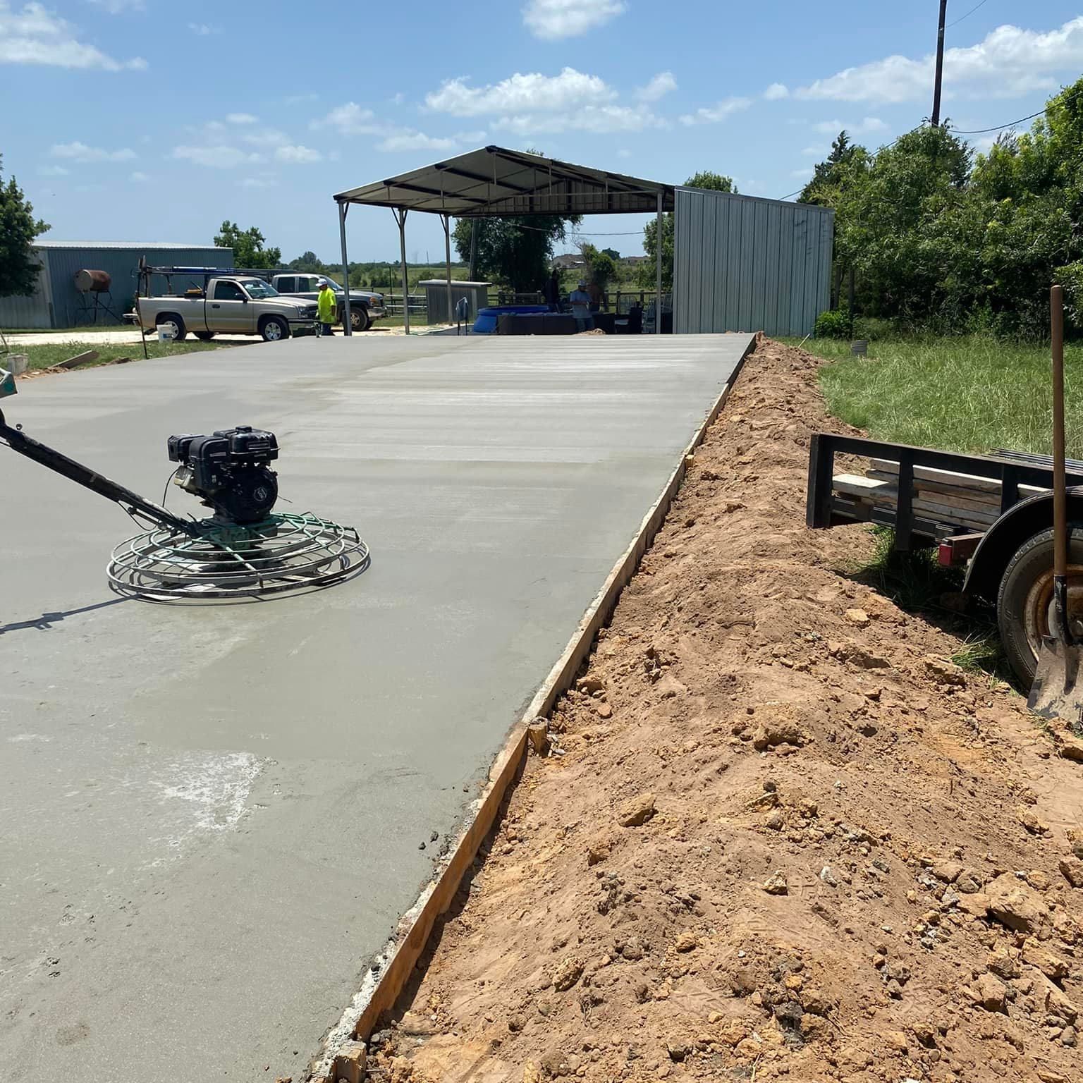 A person is using a machine to spread concrete on a road