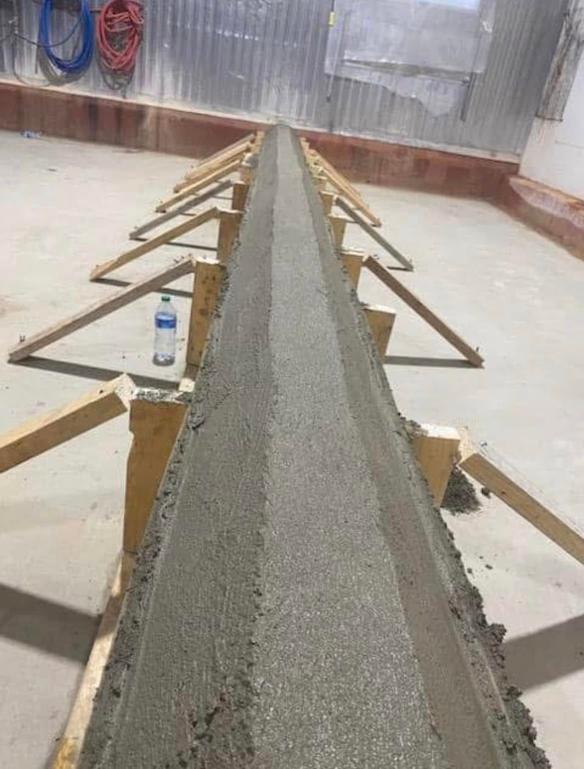 A concrete beam is being built in a room with wooden beams.